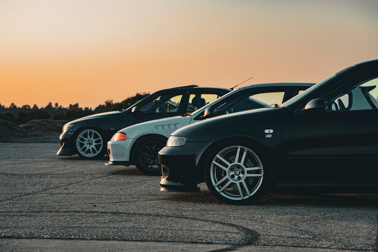 A lineup of black and white sports cars at sunset, showcasing sleek design and urban style.