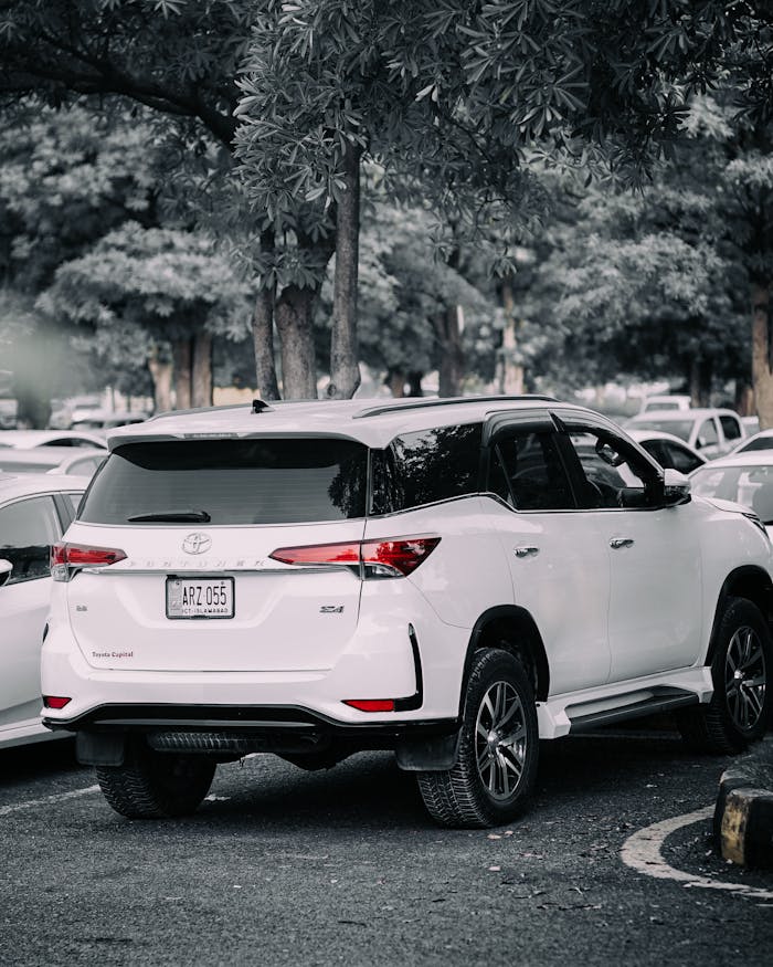 White SUV parked in a tree-lined outdoor parking lot on a clear day.